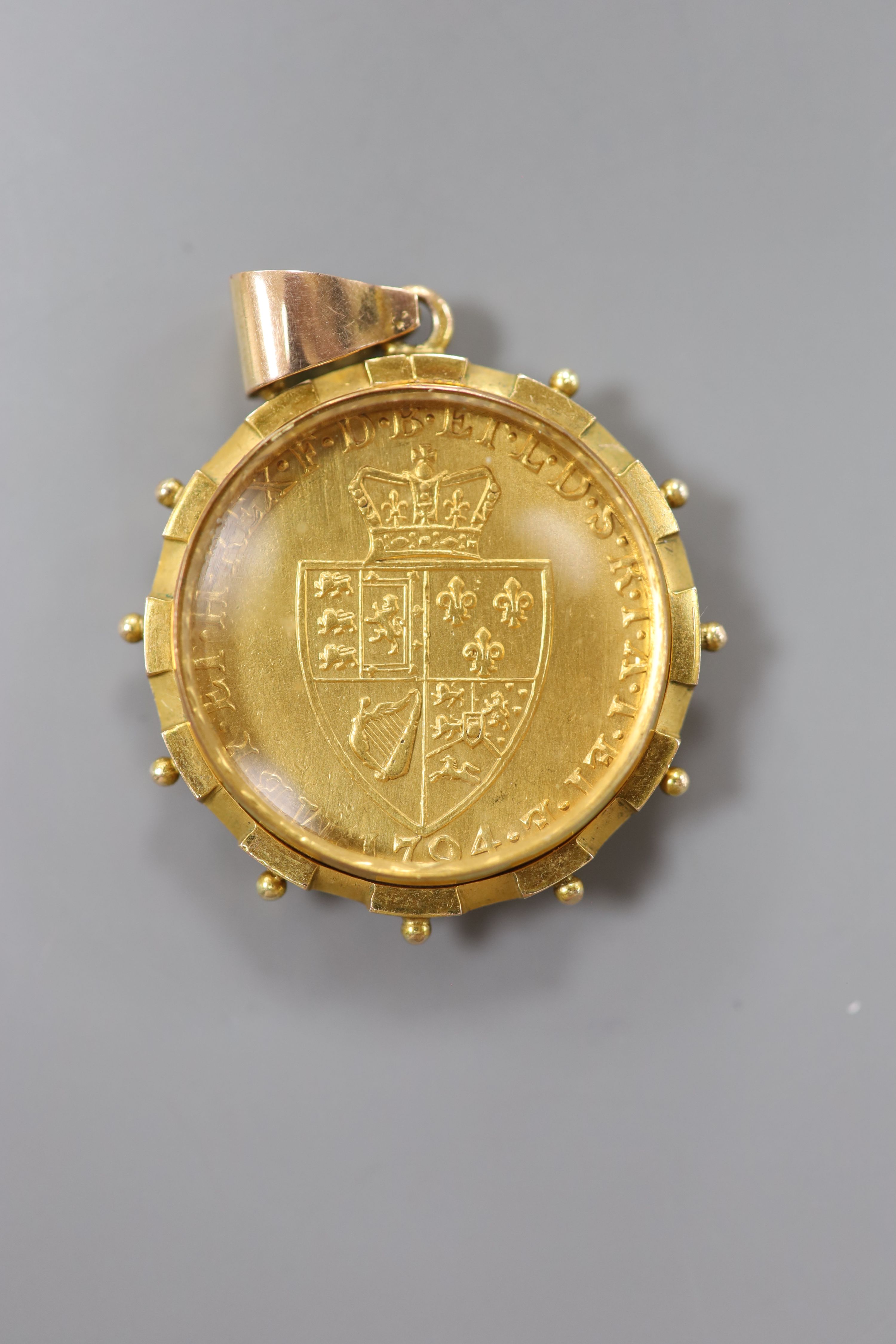 A George III spade guinea, 1794 in a glazed 9ct gold mount, gross 17.2 grams.